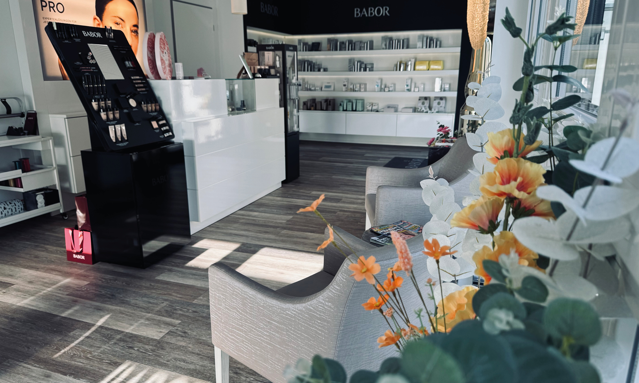 Verkaufsraum von BABOR by Kosmetik Laichingen: Empfangstresen, BABOR-PRO-Display, gefüllte Produktregale, graue Sessel.