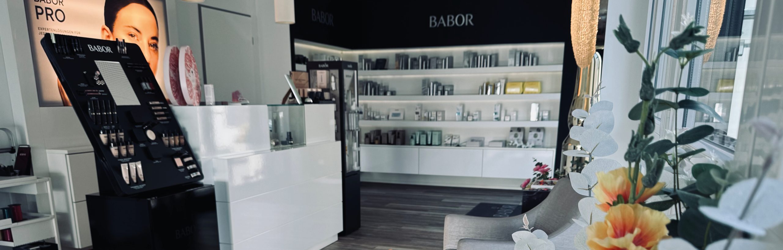 Verkaufsraum von BABOR by Kosmetik Laichingen: Empfangstresen, BABOR-PRO-Display, gefüllte Produktregale, graue Sessel.
